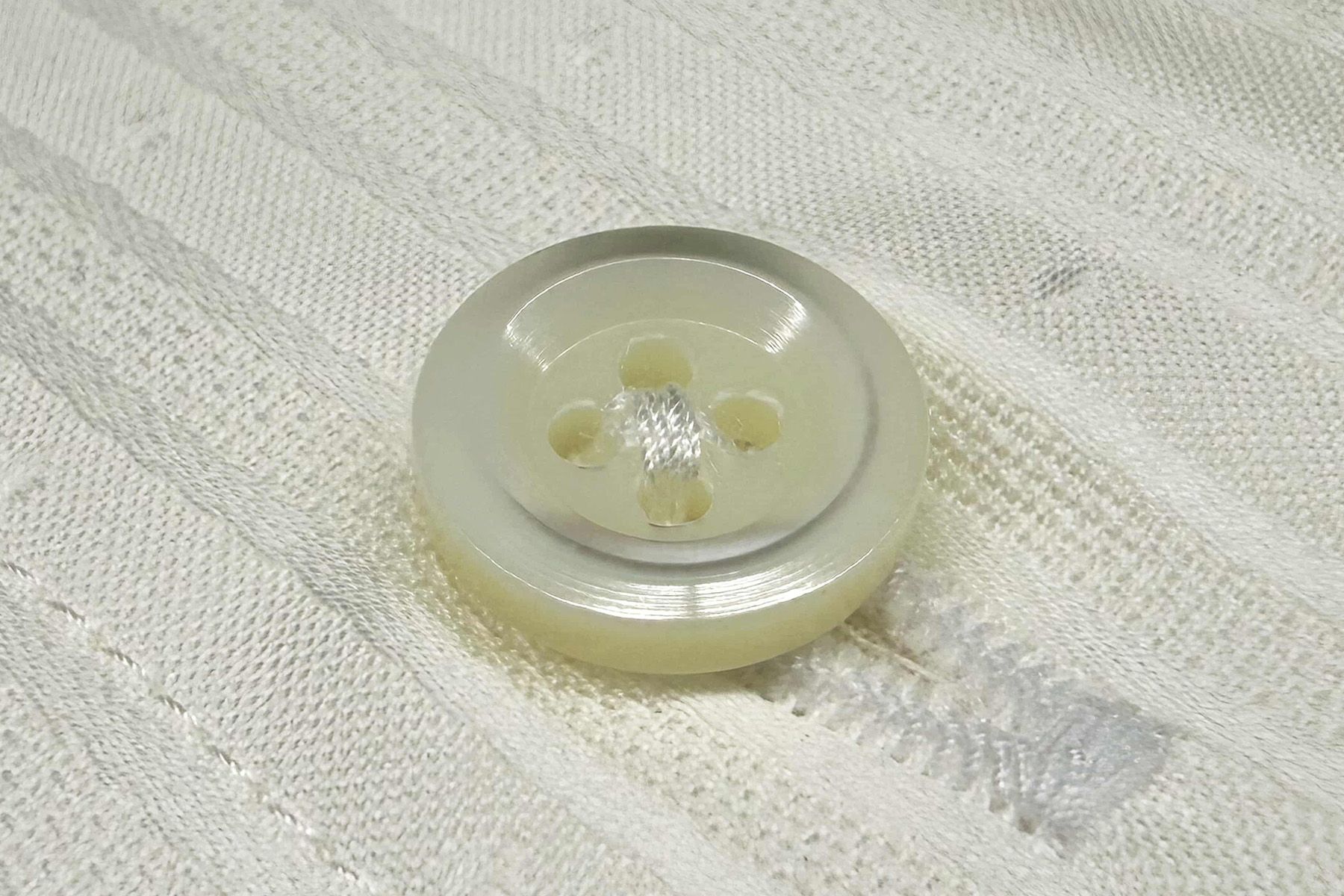シャツに縫い付けられた、厚さ2.2mmの別注貝ボタン